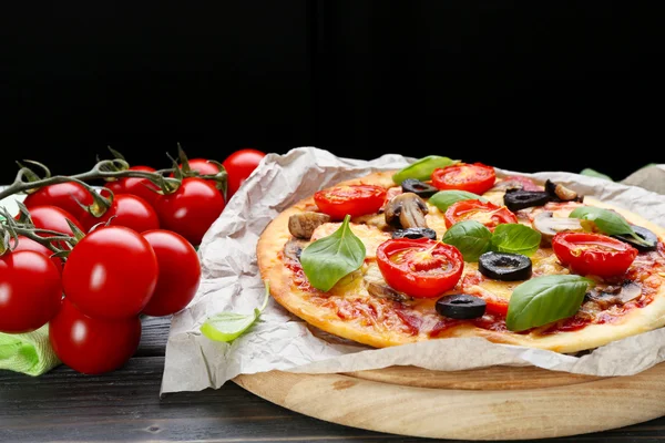 Välsmakande pizza med grönsaker och basilika på svart bakgrund — Stockfoto