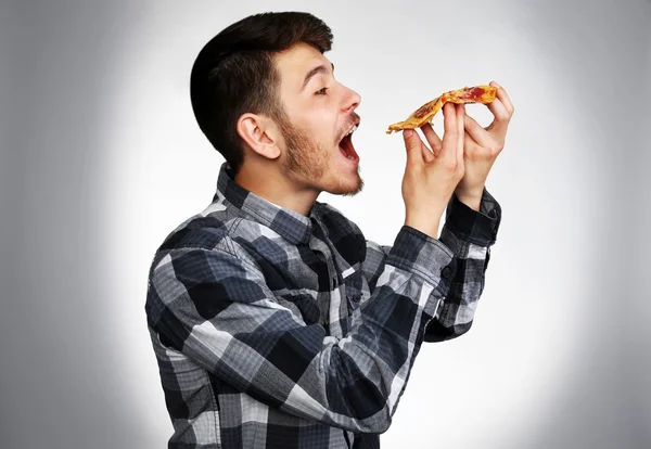 Ung Man Äta Bit Pizza Grå Bakgrund — Stockfoto