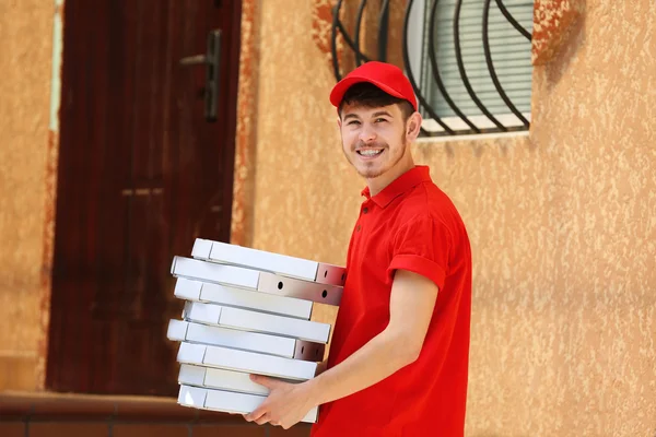 Delivery boy with cardboard pizza box near house of customer, outdoors — Stock Photo, Image