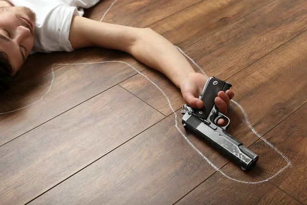 Crime scene simulation, young man lying with gun on floor — Stock Photo, Image