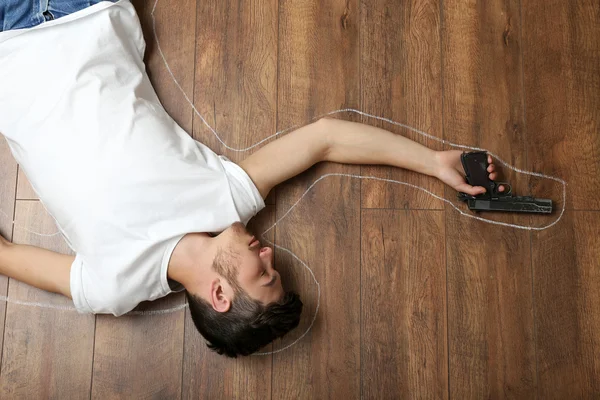 Crime scene simulation, young man lying with gun on floor — Stock Photo, Image