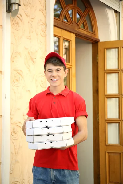 Jeune homme livrant une boîte à pizza près de la maison — Photo