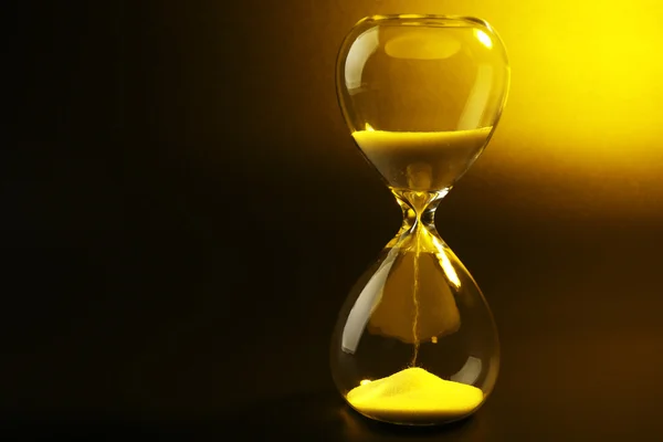 Reloj de arena sobre fondo amarillo oscuro — Foto de Stock