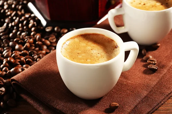 Duas xícaras de café fresco com grãos na mesa, close-up — Fotografia de Stock