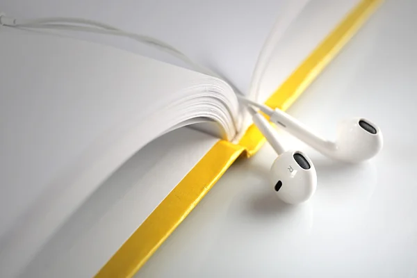 Earphones and book on table, closeup — Stock Photo, Image