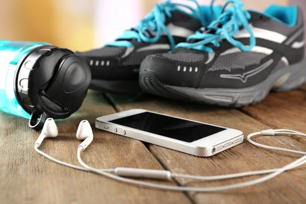 Sneakers dan earphone di atas meja kayu, close-up — Stok Foto