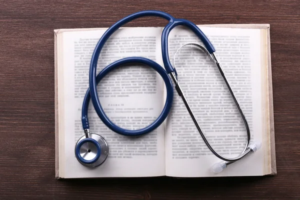 Stethoscope on book on wooden table — Stock Photo, Image