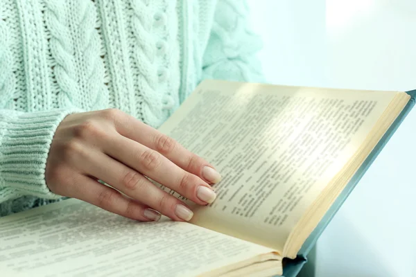 Kvinna läser bok nära fönstret — Stockfoto