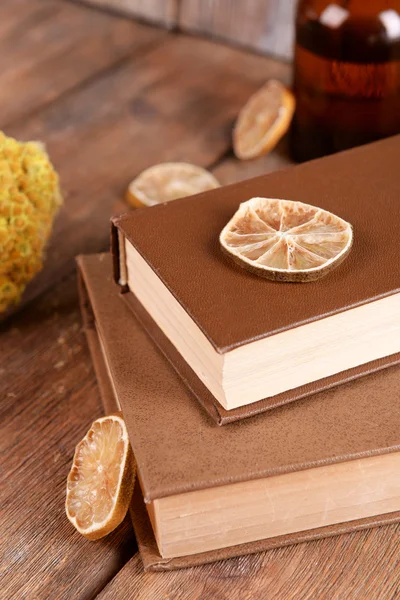 Oude boeken met droge bloemen en citroen op houten achtergrond — Stockfoto