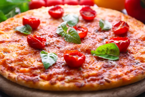 Pizza s bazalkou a cherry rajčátky na dřevěné prkénko, detail — Stock fotografie