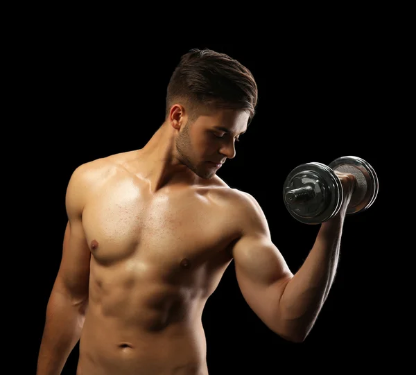 Muscolo giovane uomo in possesso di manubri su sfondo scuro — Foto Stock