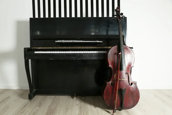 Виолончель рядом с фортепиано на белом фоне — стоковое фото
