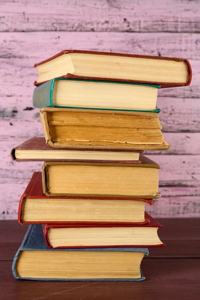 Pilha de livros sobre mesa de madeira sobre fundo de parede de madeira rosa — Fotografia de Stock