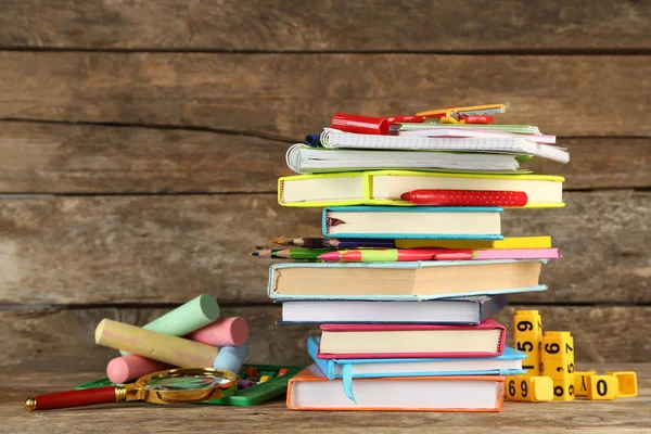 Stapel von Büchern und Schreibwaren auf Holzgrund — Stockfoto