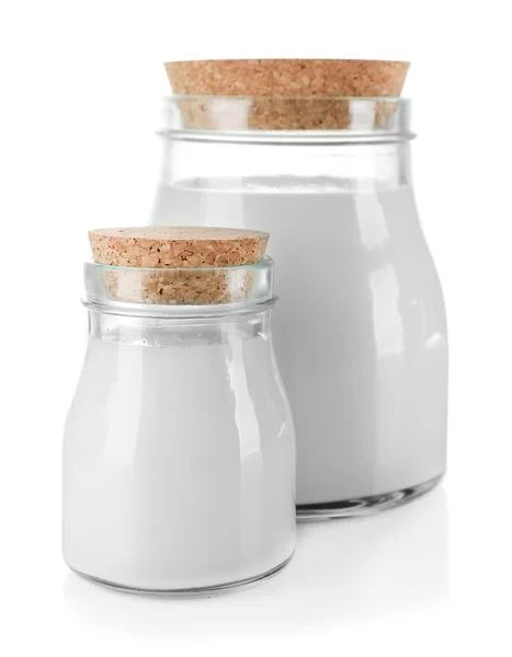 Słoiki szklane mleka na drewnianym stole, na białym tle — Zdjęcie stockowe