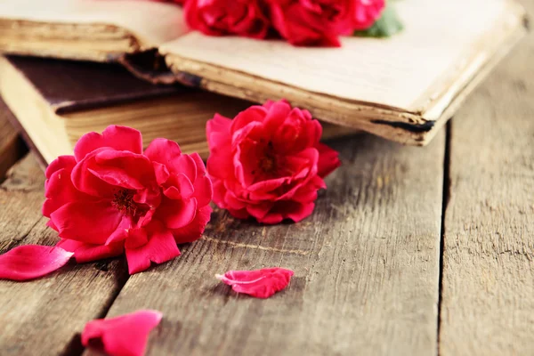 Old books with beautiful flowers on wooden table close up — Stock Photo, Image