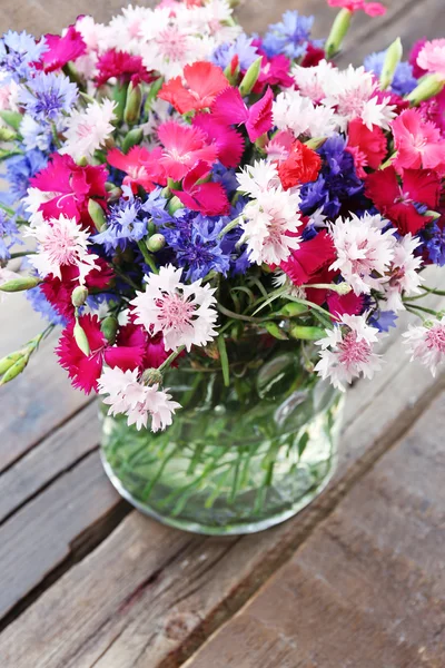 Krásné malé kytice ve váze na dřevěné pozadí — Stock fotografie
