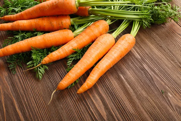 Fresh organic carrots with green tops on wooden table, closeup — Stock Photo, Image