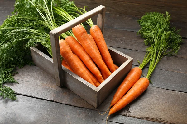 Frische Bio-Karotten in Kiste auf Holzgrund — Stockfoto