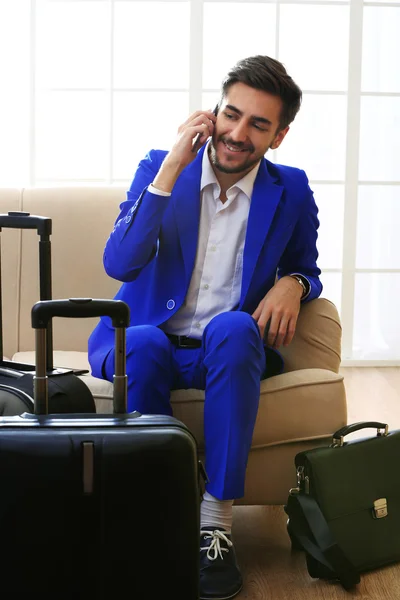 Hombre de negocios con maletas sentado en el sofá en el pasillo — Foto de Stock