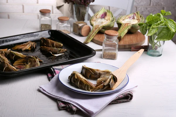 Geröstete Artischocken auf Teller, auf Küchentisch Hintergrund — Stockfoto