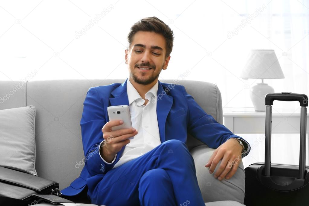Business man with suitcase sitting on sofa at home
