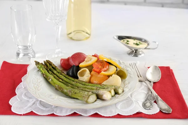 Gebratener Spargel und leckere bunte Pasta mit Gemüse auf Teller auf Holztischhintergrund — Stockfoto