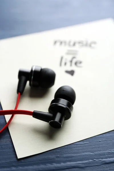 Earphones with text Music - life on sticker on wooden table, closeup