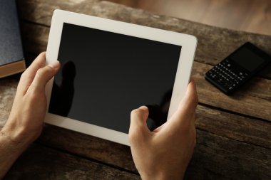 Ahşap masa arka plan üzerinde dijital tablet holding eller