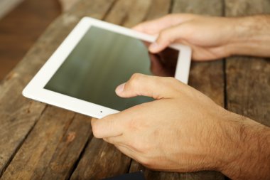 Ahşap masa arka plan üzerinde dijital tablet holding eller