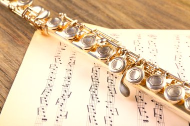 Ahşap masa üzerine müzik notlar ile gümüş flüt yakın çekim