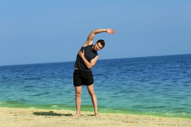 Genç adam sportif plajda egzersiz yaparak