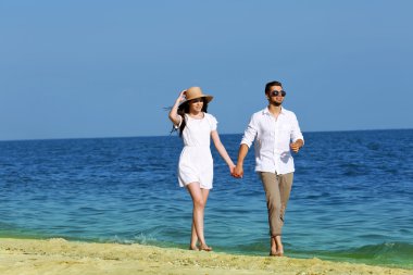 Genç bir çift sahilde yürüyor.