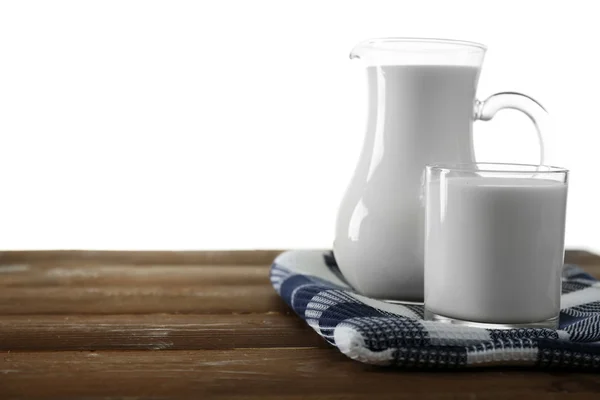 Jarra y vaso de leche sobre mesa de madera, sobre fondo blanco — Foto de Stock