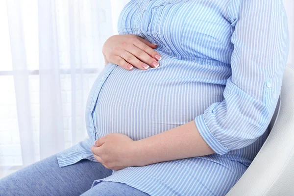 Vacker ung gravid kvinna röra hennes mage på ljus bakgrund — Stockfoto