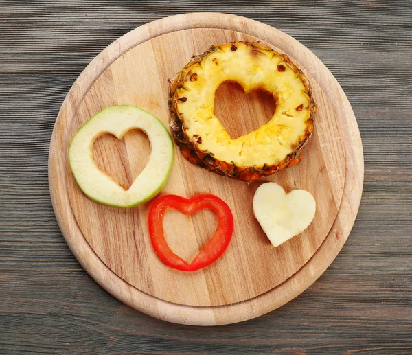 Fruits slices with cut in shape of heart on wooden background — Stock Photo, Image