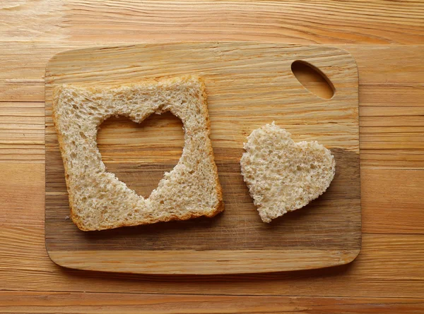 Fatia de pão com corte em forma de coração no fundo de madeira — Fotografia de Stock