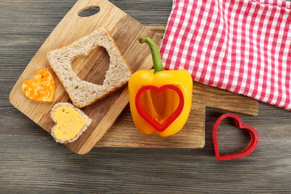 Хлеб нарезанный в форме сердца и перца на столе крупным планом — стоковое фото