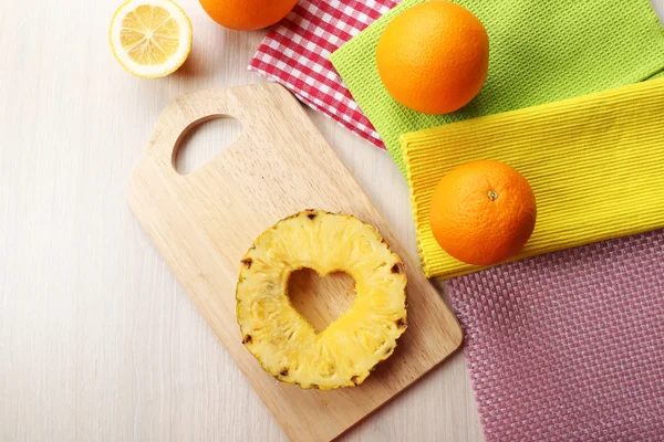 Pineapple slice with cut in shape of heart and different fruits on table close up — Stock Photo, Image