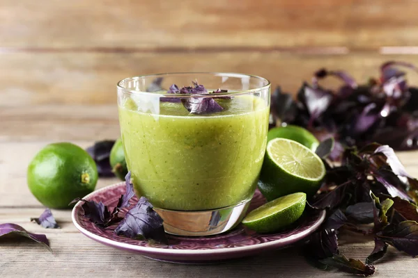 Glass of green healthy juice with basil and limes on table close up — Stock Photo, Image