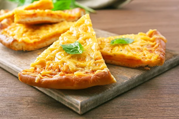 Rebanadas de sabrosa pizza de queso con albahaca en la mesa de cerca —  Fotos de Stock