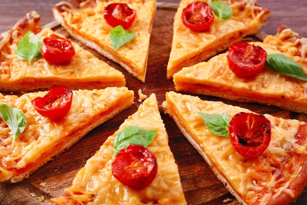 Plastry smaczny ser do pizzy z bazylią i pomidorkami na stole z bliska — Zdjęcie stockowe