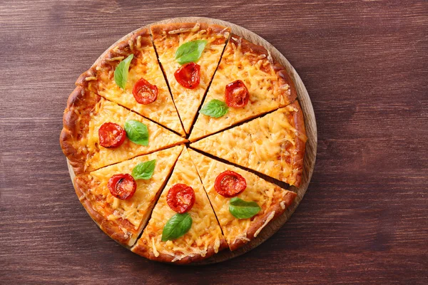 Fette di gustosa pizza al formaggio con basilico e pomodorini sul tavolo da vicino — Foto Stock