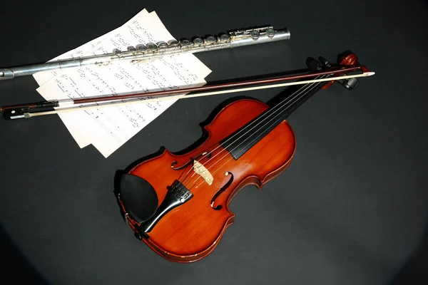 Violino e flauto con note musicali su sfondo scuro — Foto Stock