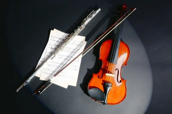 Geige und Flöte mit Noten auf dunklem Hintergrund — Stockfoto