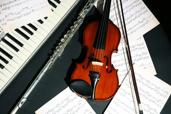 Instrumentos musicais com notas de música sobre fundo escuro — Fotografia de Stock