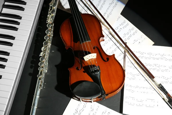 Instrumentos musicais com notas de música sobre fundo escuro — Fotografia de Stock