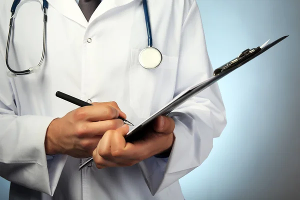 Médico masculino con carpeta sobre fondo azul — Foto de Stock