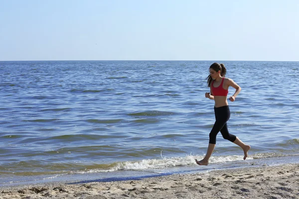 Ung kvinna jogging på stranden — Stockfoto