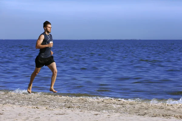 Ung man joggar på stranden — Stockfoto